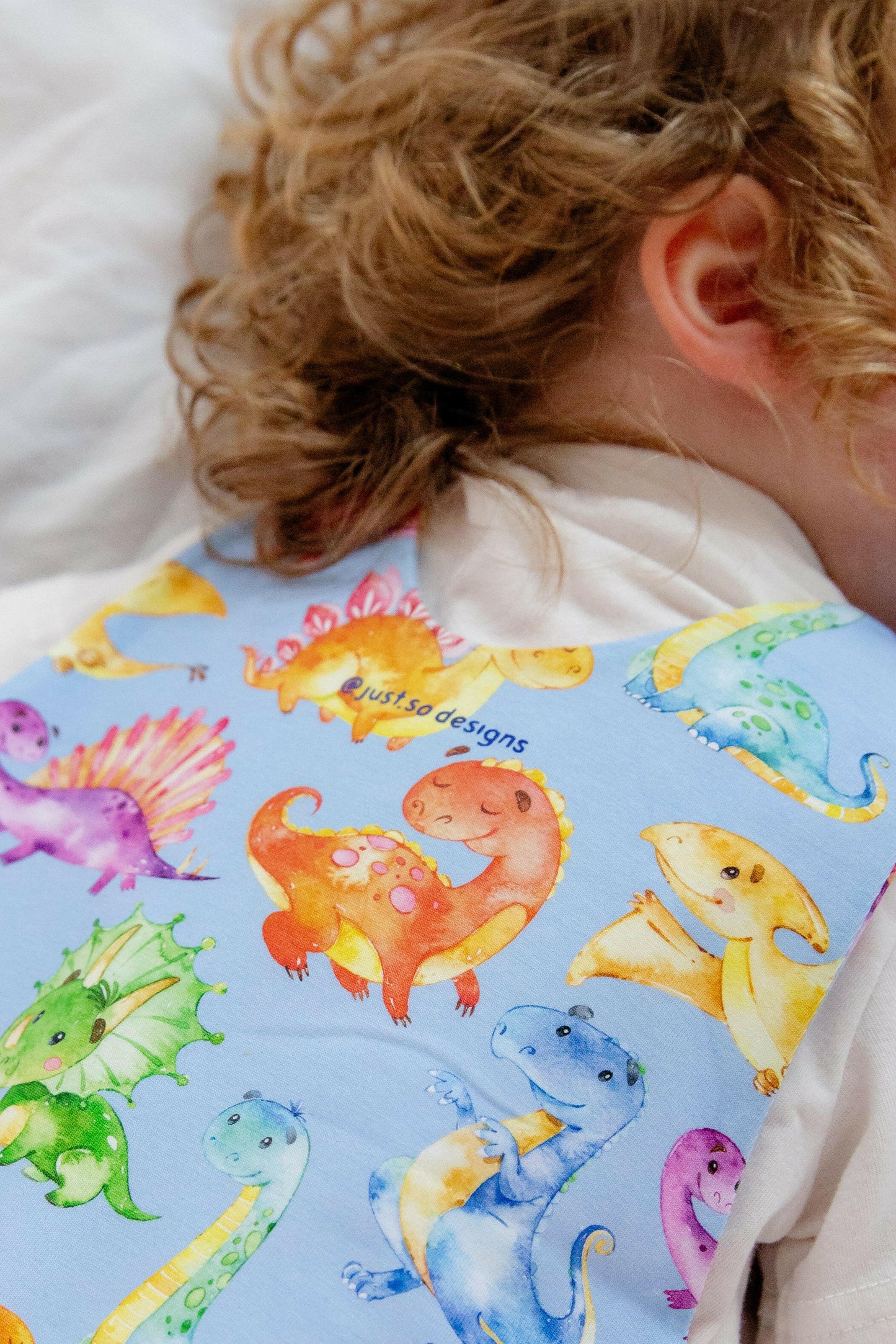 Blue cute dinosaur print romper handmade for babies and toddlers, fun for running, jumping and climbing. Dungarees style outfit in a stretchy cotton fabric handmade in Oxfordshire.