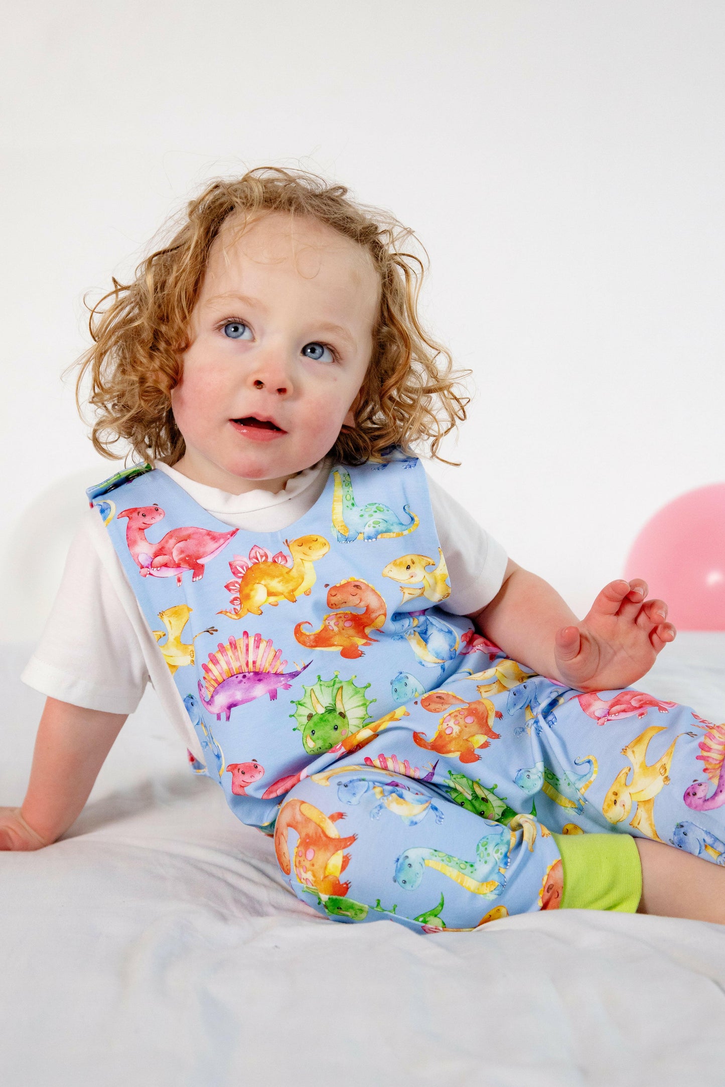 Blue cute dinosaur print romper handmade for babies and toddlers, fun for running, jumping and climbing. Dungarees style outfit in a stretchy cotton fabric handmade in Oxfordshire.