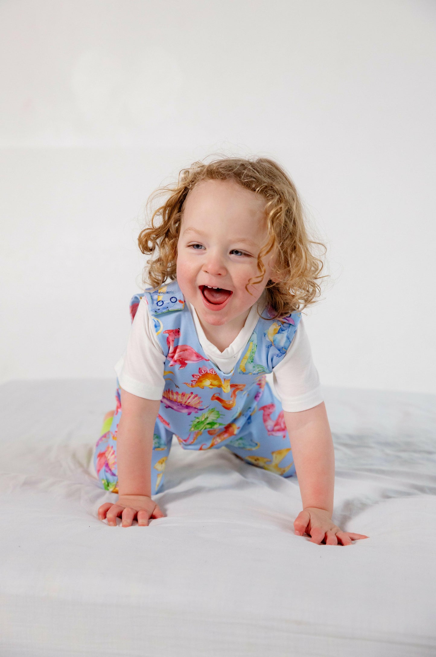 Blue cute dinosaur print romper handmade for babies and toddlers, fun for running, jumping and climbing. Dungarees style outfit in a stretchy cotton fabric handmade in Oxfordshire.