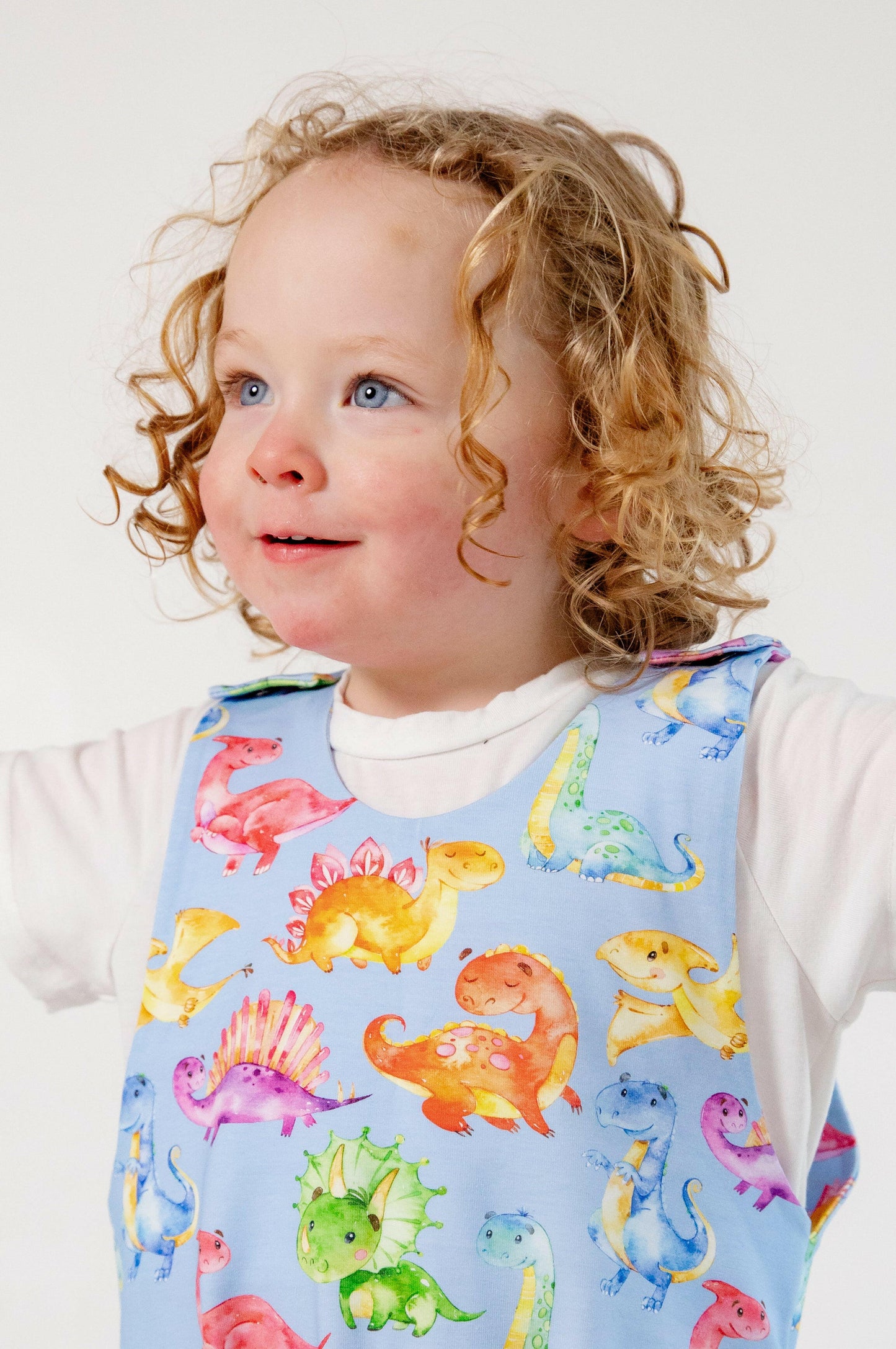 Blue cute dinosaur print romper handmade for babies and toddlers, fun for running, jumping and climbing. Dungarees style outfit in a stretchy cotton fabric handmade in Oxfordshire.