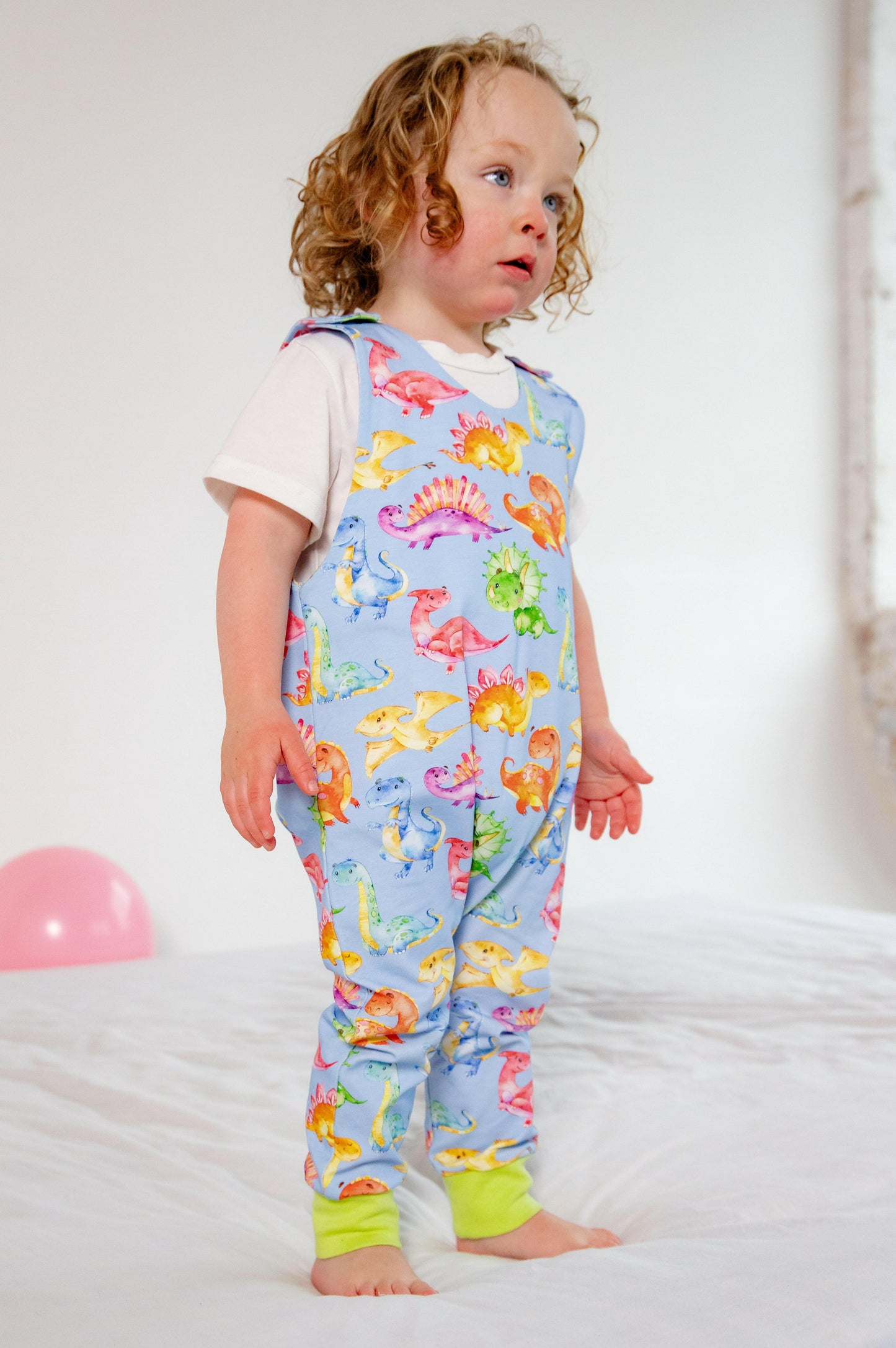 Blue cute dinosaur print romper handmade for babies and toddlers, fun for running, jumping and climbing. Dungarees style outfit in a stretchy cotton fabric handmade in Oxfordshire.