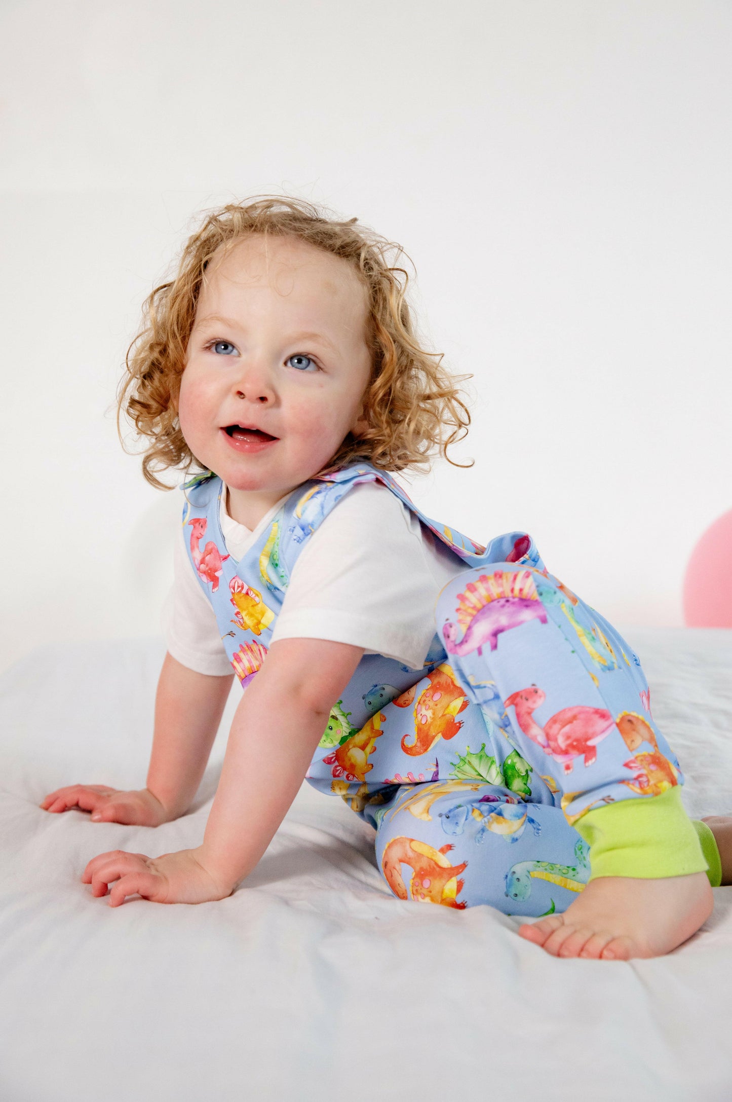Blue cute dinosaur print romper handmade for babies and toddlers, fun for running, jumping and climbing. Dungarees style outfit in a stretchy cotton fabric handmade in Oxfordshire.