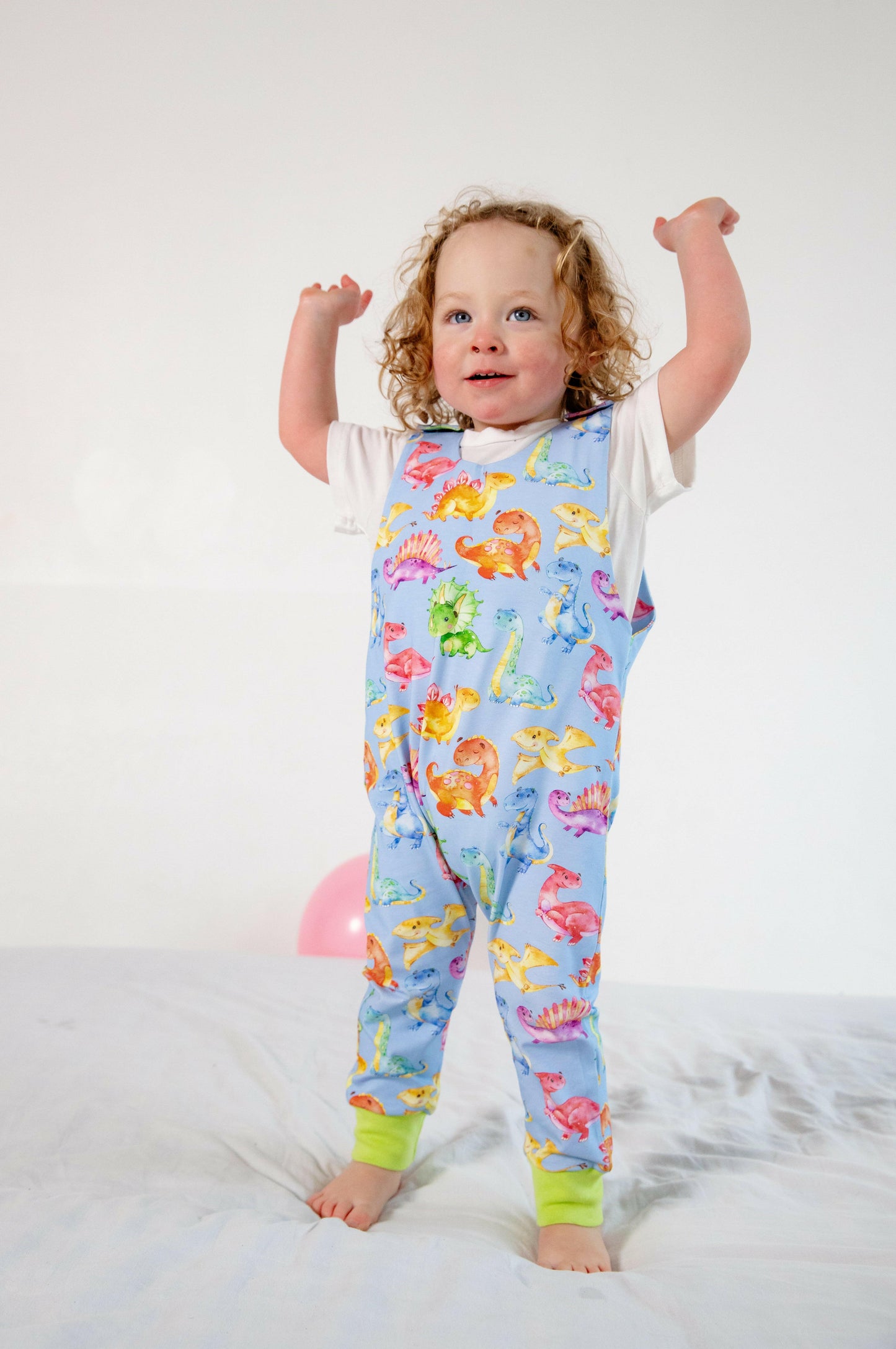 Blue cute dinosaur print romper handmade for babies and toddlers, fun for running, jumping and climbing. Dungarees style outfit in a stretchy cotton fabric handmade in Oxfordshire.