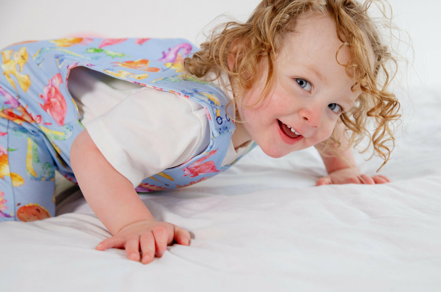 Blue cute dinosaur print romper handmade for babies and toddlers, fun for running, jumping and climbing. Dungarees style outfit in a stretchy cotton fabric handmade in Oxfordshire.