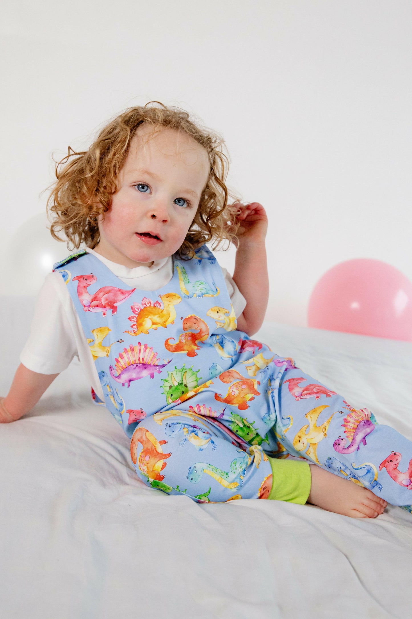 Blue cute dinosaur print romper handmade for babies and toddlers, fun for running, jumping and climbing. Dungarees style outfit in a stretchy cotton fabric handmade in Oxfordshire.