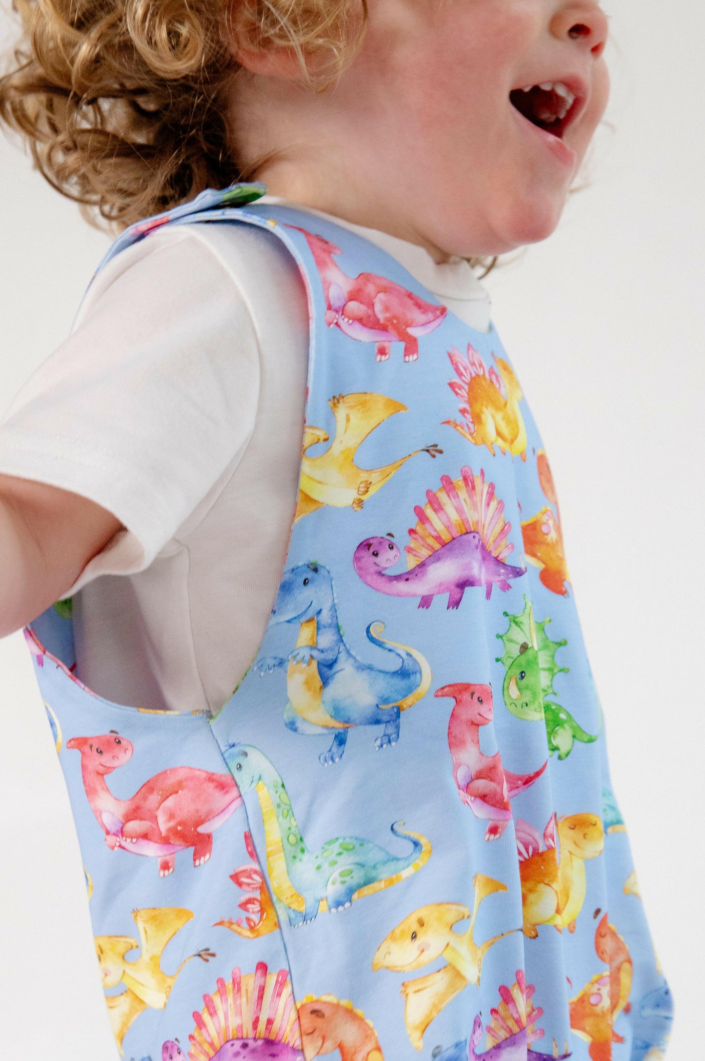 Blue cute dinosaur print romper handmade for babies and toddlers, fun for running, jumping and climbing. Dungarees style outfit in a stretchy cotton fabric handmade in Oxfordshire.
