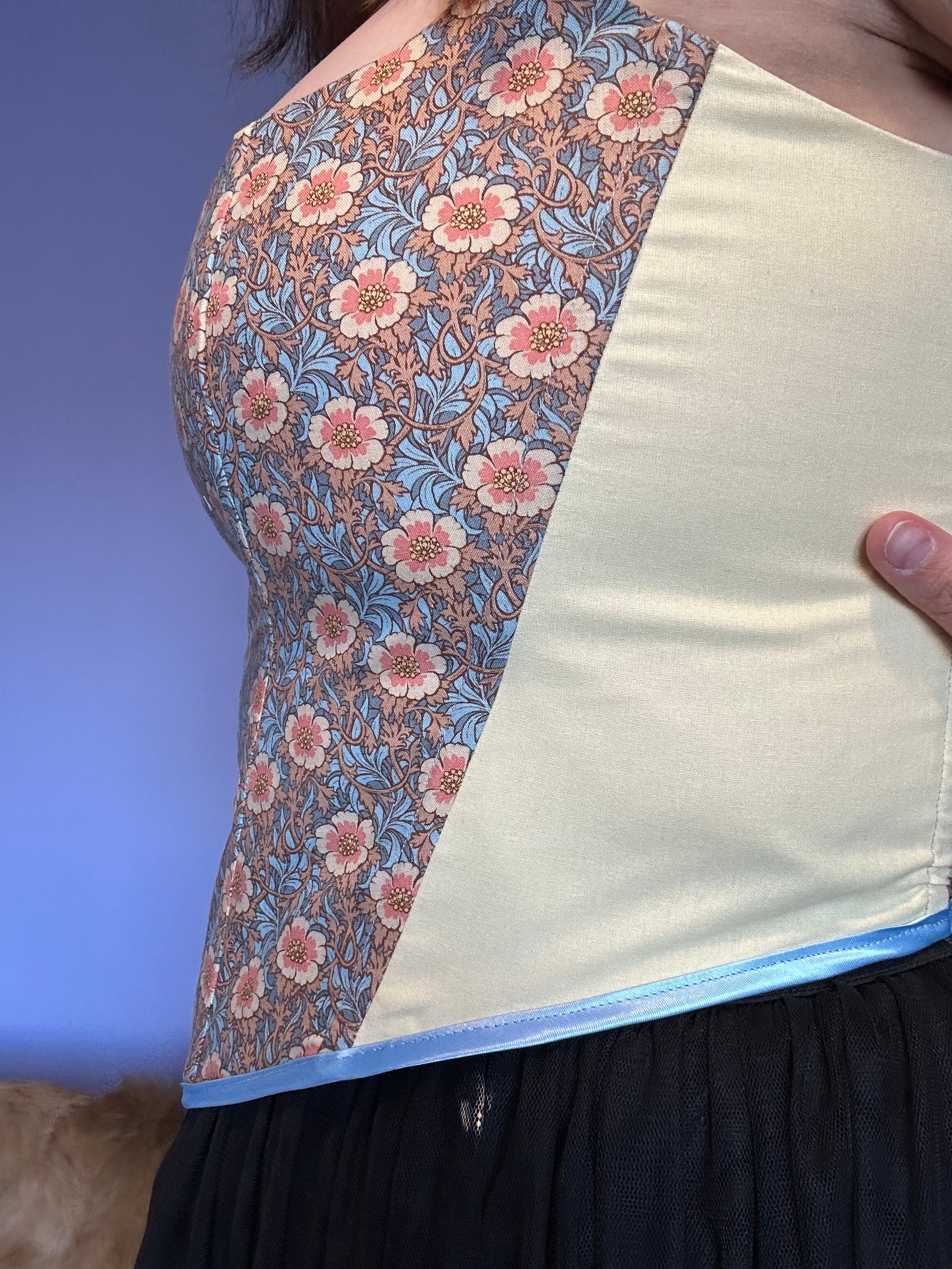 Handmade boned corset featuring a vintage floral print with soft cream side panels. Designed for both comfort and style, this unique piece blends classic craftsmanship with modern elegance.