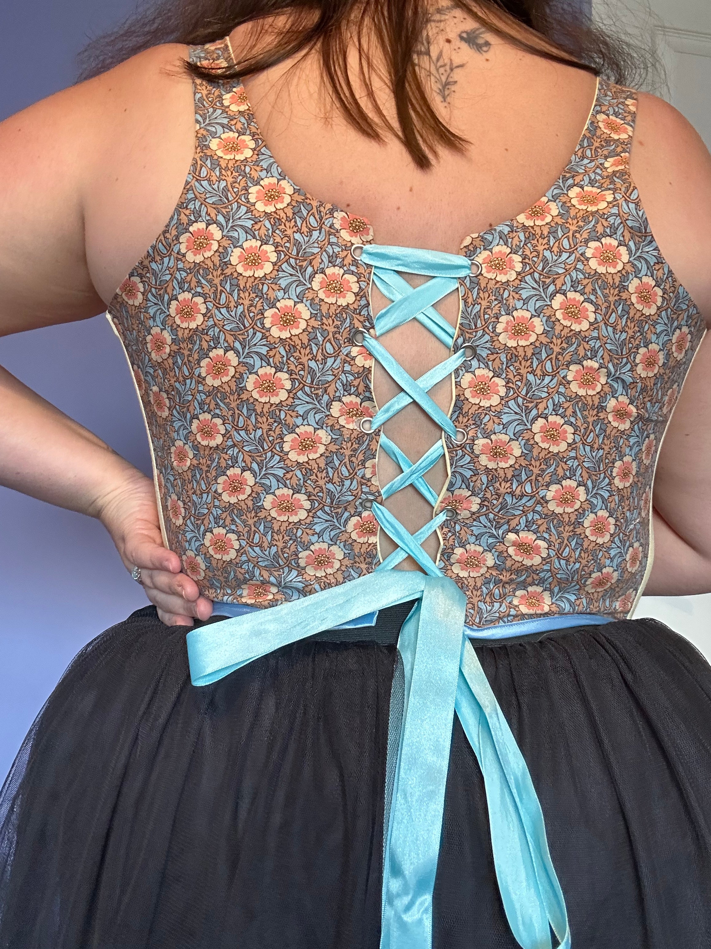 Handmade boned corset featuring a vintage floral print with soft cream side panels. Designed for both comfort and style, this unique piece blends classic craftsmanship with modern elegance.