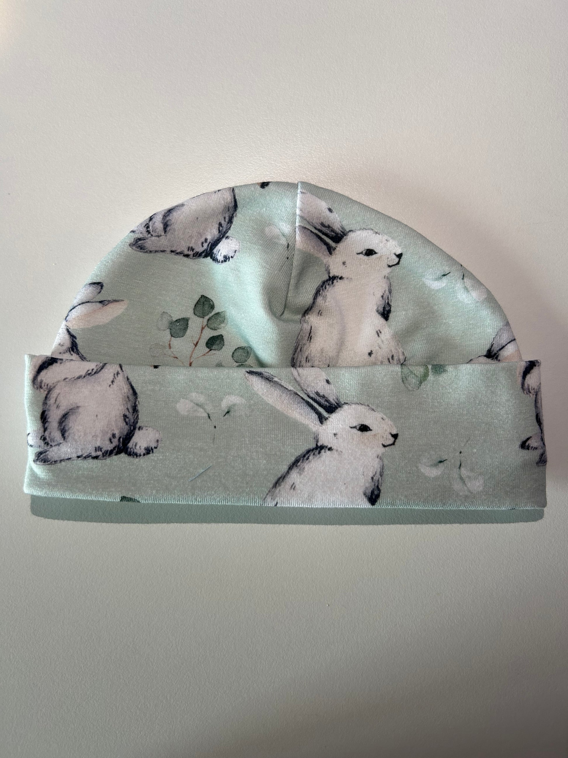 Baby hat with green bunnies pattern, handmade in Oxfordshire