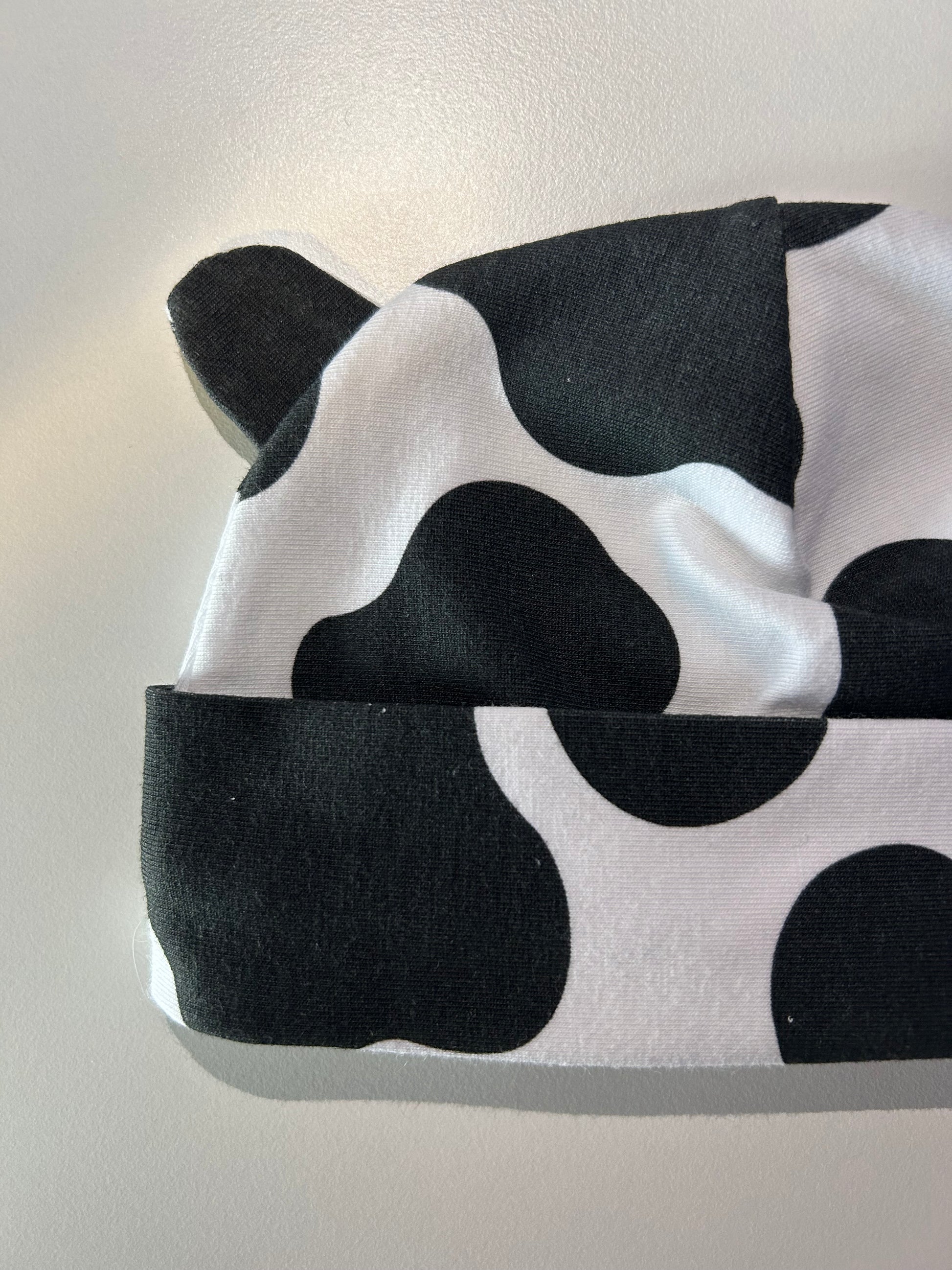 Baby hat with bold cow pattern, handmade in Oxfordshire