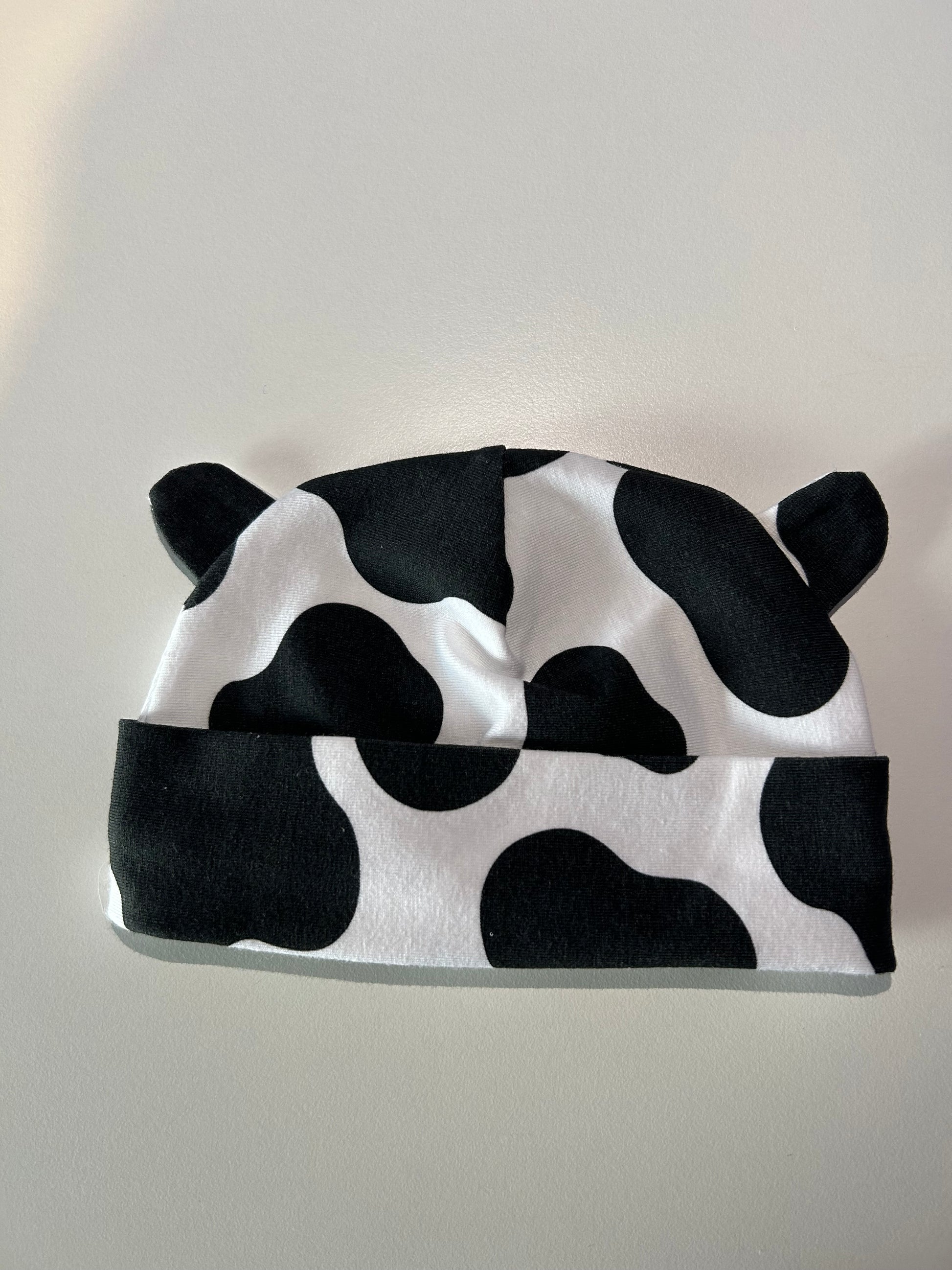 Baby hat with bold cow pattern, handmade in Oxfordshire