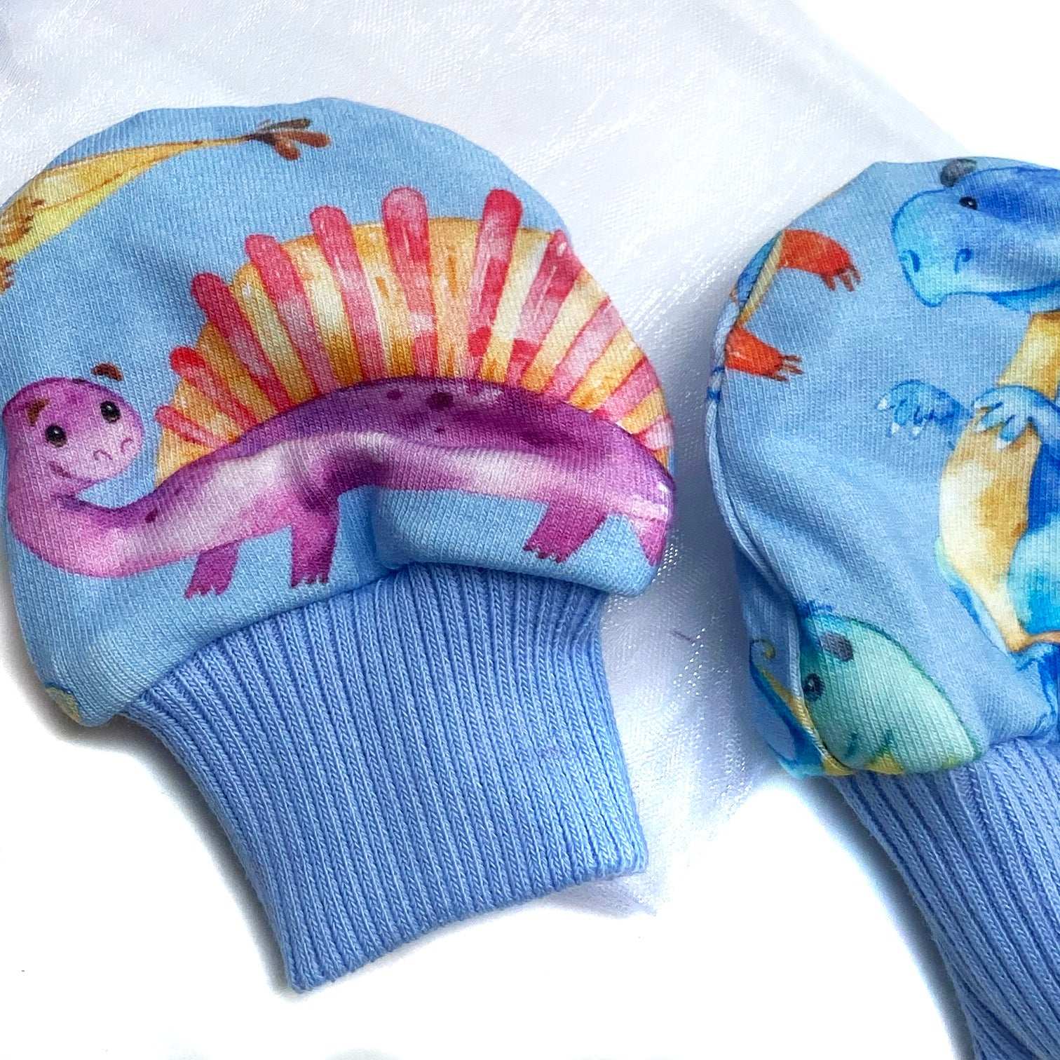 Gorgeous little baby mittens in a bold blue dinosaur print, perfect for baby gifts, growing hands to give plenty of movement and to match outfits. 