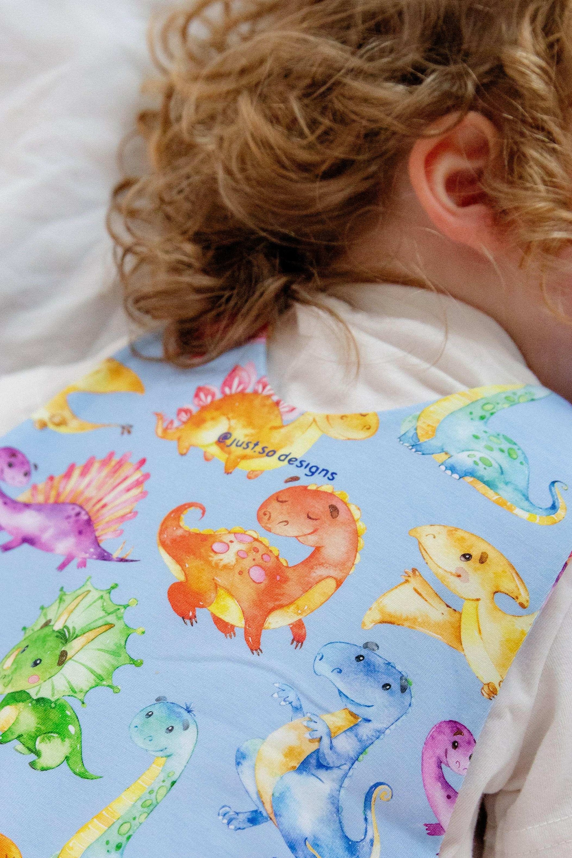 Blue cute dinosaur print romper handmade for babies and toddlers, fun for running, jumping and climbing. Dungarees style outfit in a stretchy cotton fabric handmade in Oxfordshire.