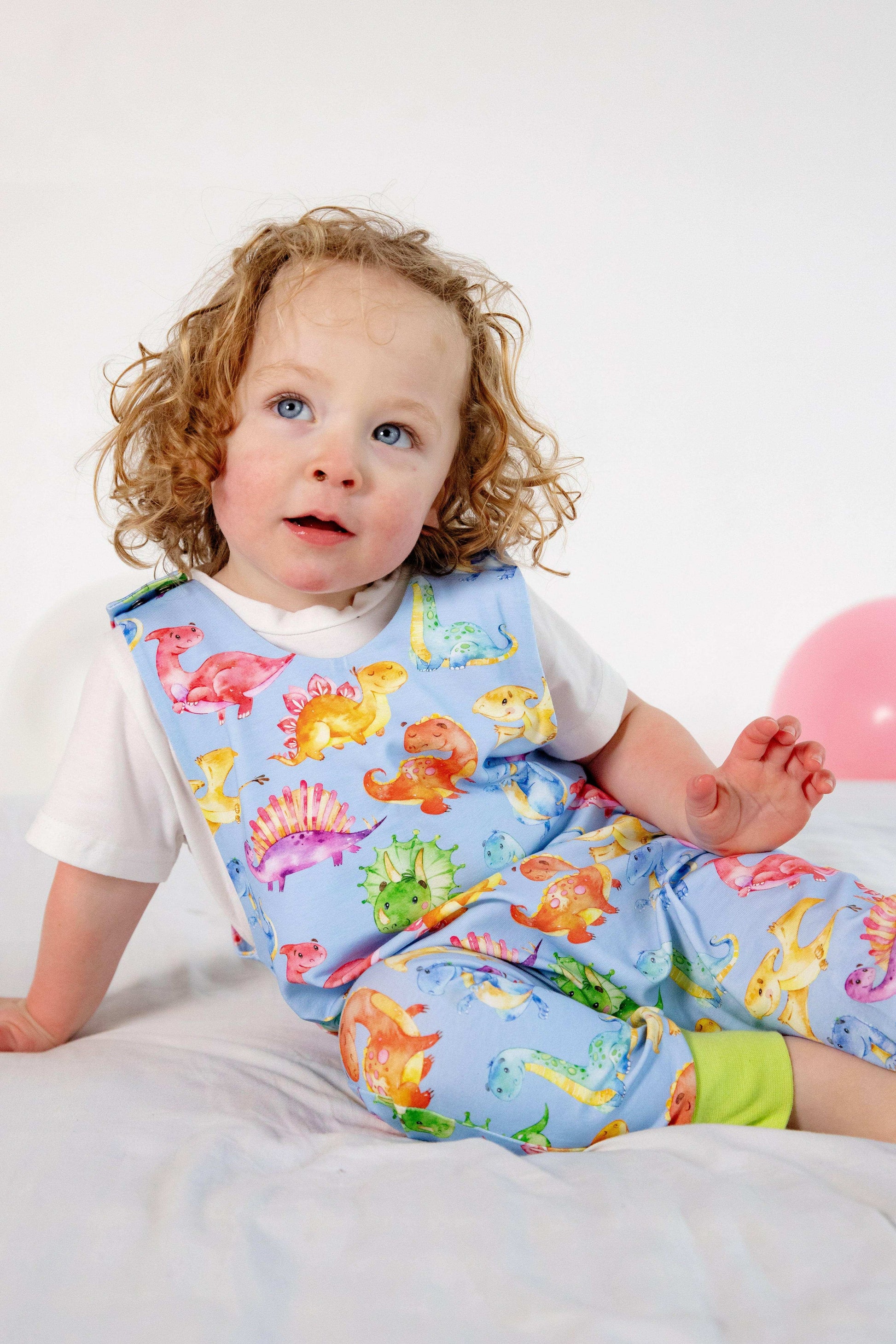 Blue cute dinosaur print romper handmade for babies and toddlers, fun for running, jumping and climbing. Dungarees style outfit in a stretchy cotton fabric handmade in Oxfordshire.