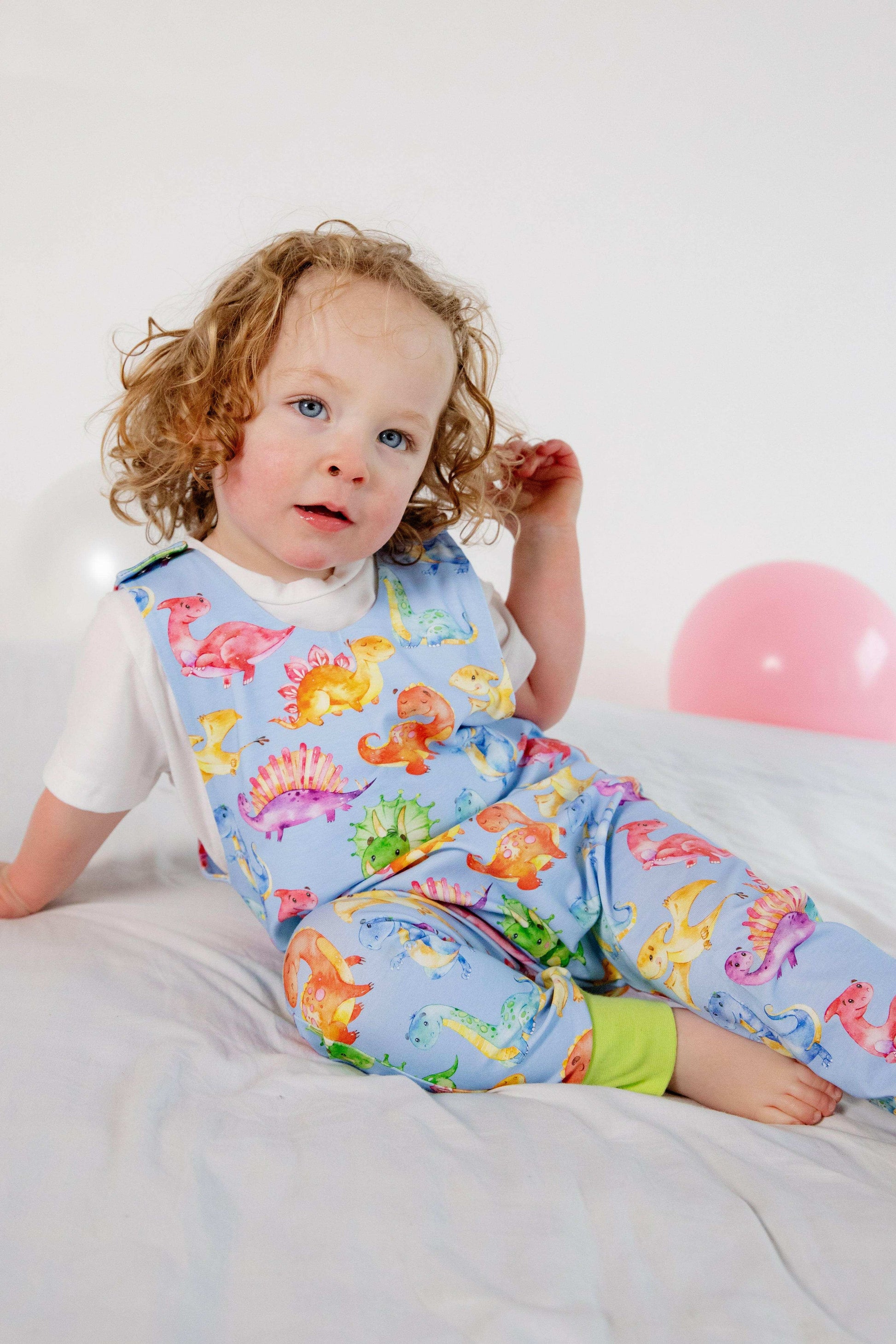 Blue cute dinosaur print romper handmade for babies and toddlers, fun for running, jumping and climbing. Dungarees style outfit in a stretchy cotton fabric handmade in Oxfordshire.