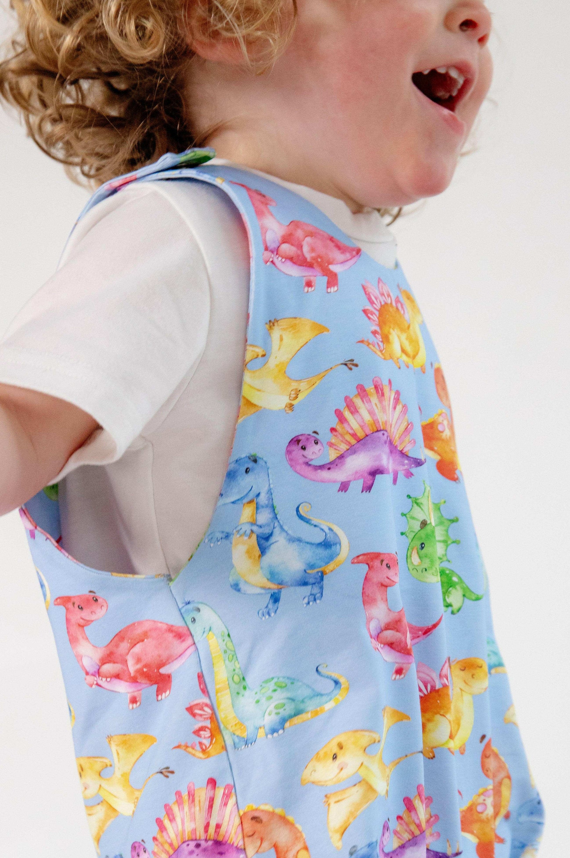 Blue cute dinosaur print romper handmade for babies and toddlers, fun for running, jumping and climbing. Dungarees style outfit in a stretchy cotton fabric handmade in Oxfordshire.