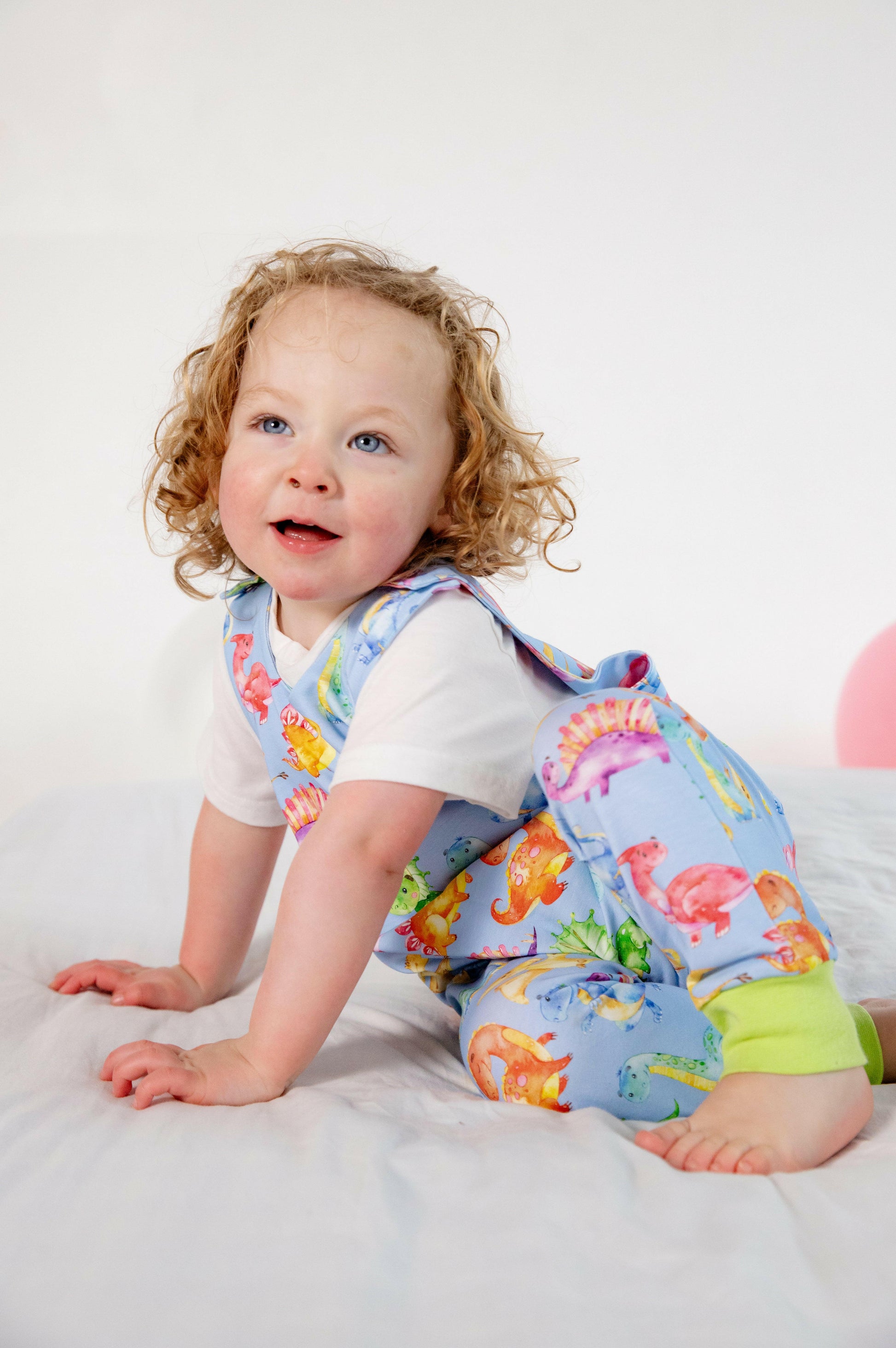 Blue cute dinosaur print romper handmade for babies and toddlers, fun for running, jumping and climbing. Dungarees style outfit in a stretchy cotton fabric handmade in Oxfordshire.