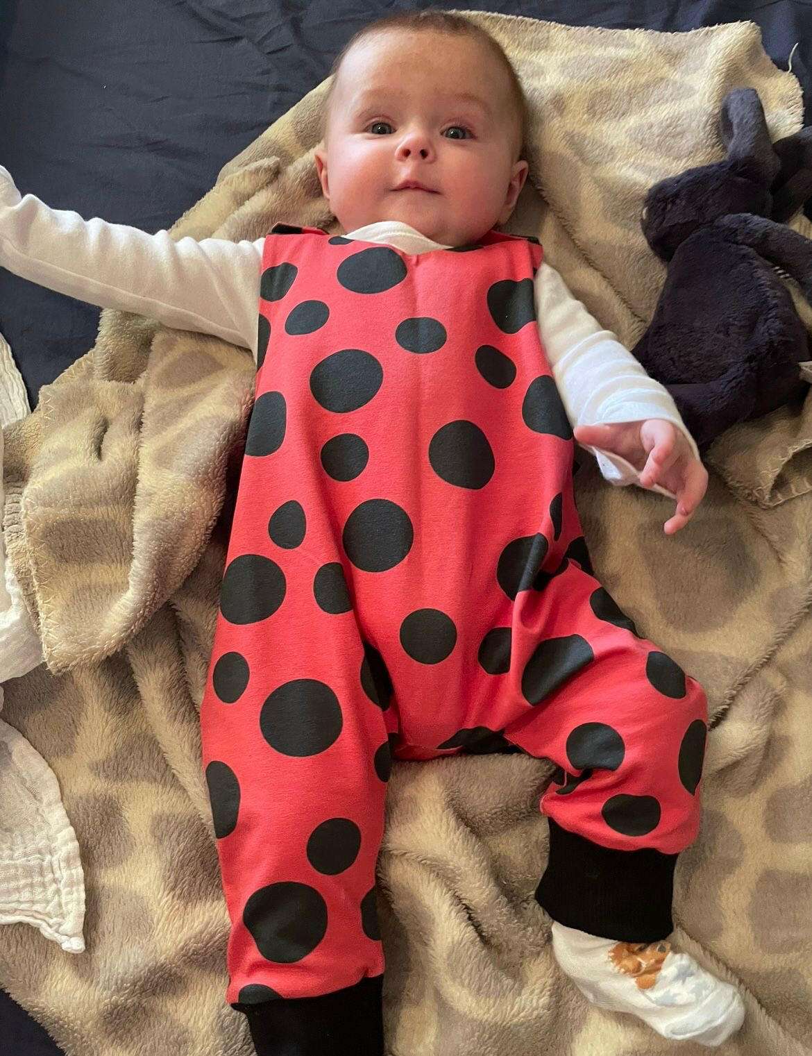 Red and black ladybird print romper handmade for babies and toddlers, fun for running, jumping and climbing. Dungarees style outfit in a stretchy cotton fabric handmade in Oxfordshire.