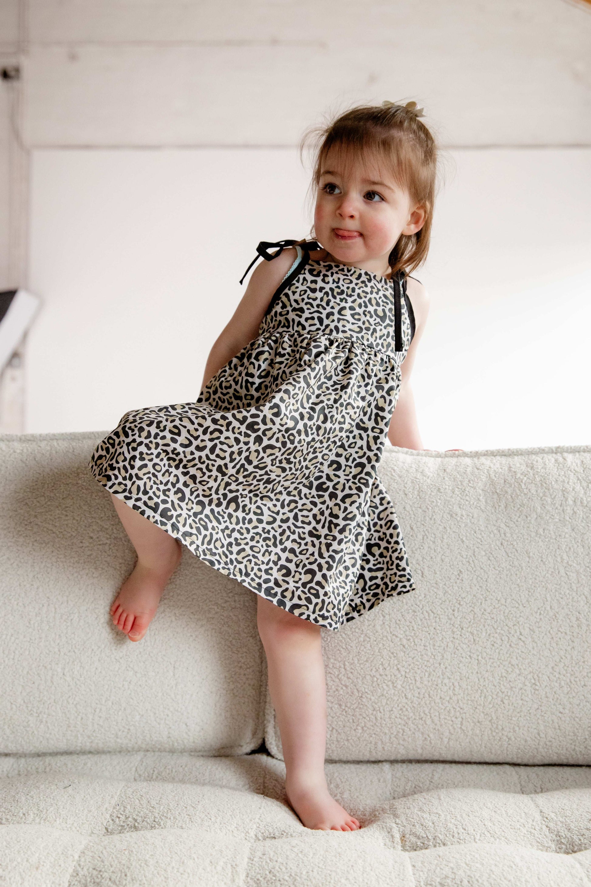 This handmade cotton dress features a bold leopard print, soft gathered skirt, and sweet bow-tie shoulder straps. Perfect for stylish little explorers with big personalities.