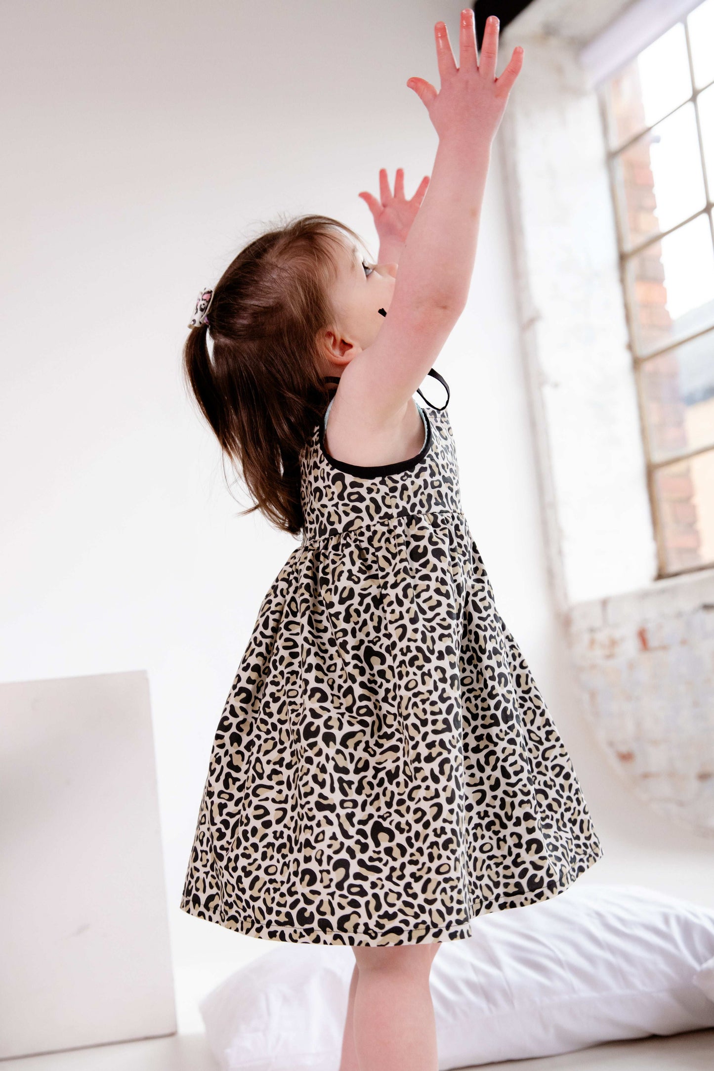 This handmade cotton dress features a bold leopard print, soft gathered skirt, and sweet bow-tie shoulder straps. Perfect for stylish little explorers with big personalities.