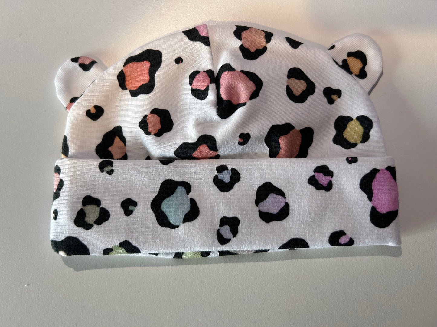 Baby hat with pastel leopard pattern, handmade in Oxfordshire