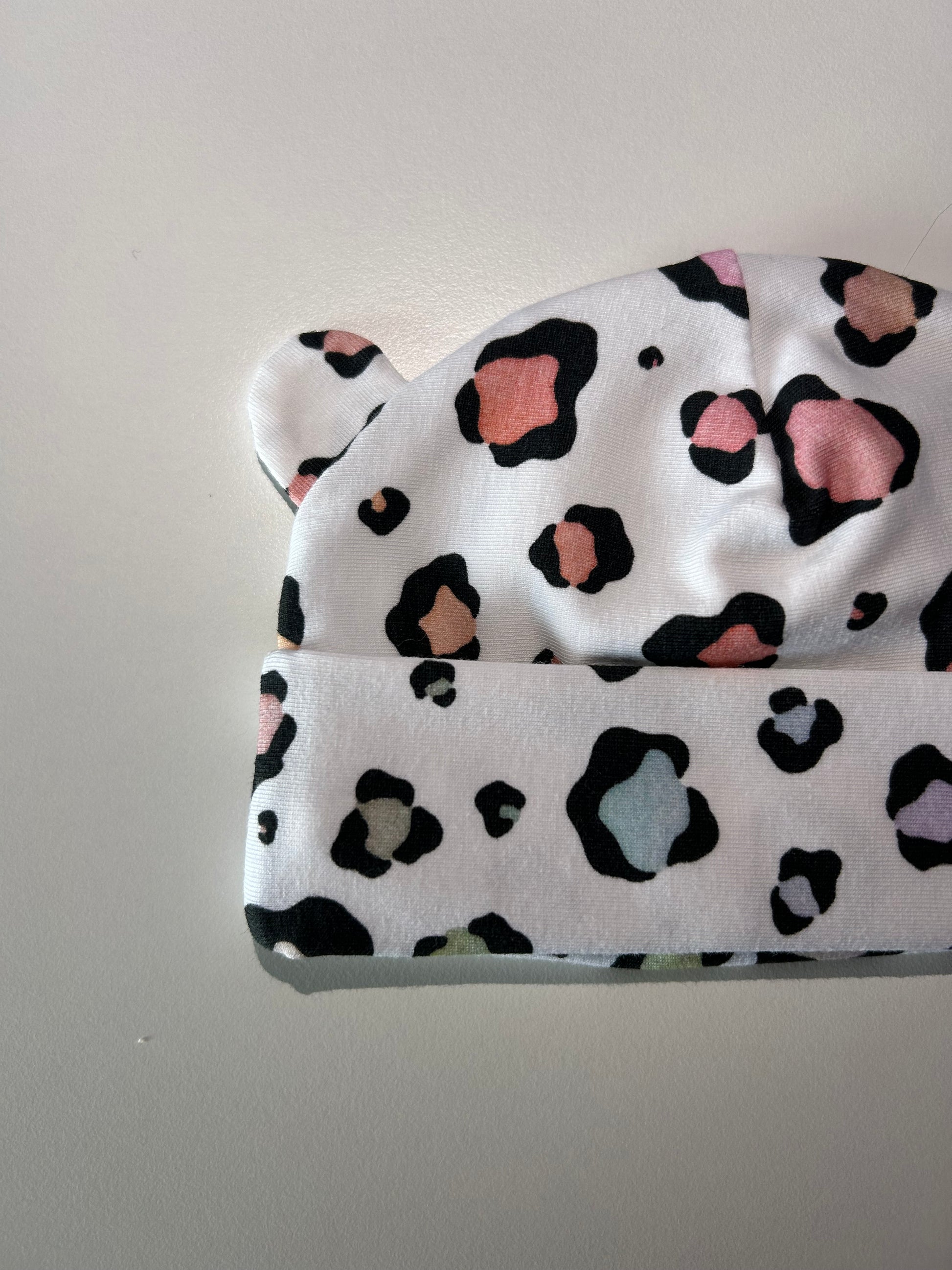 Baby hat with pastel leopard pattern, handmade in Oxfordshire