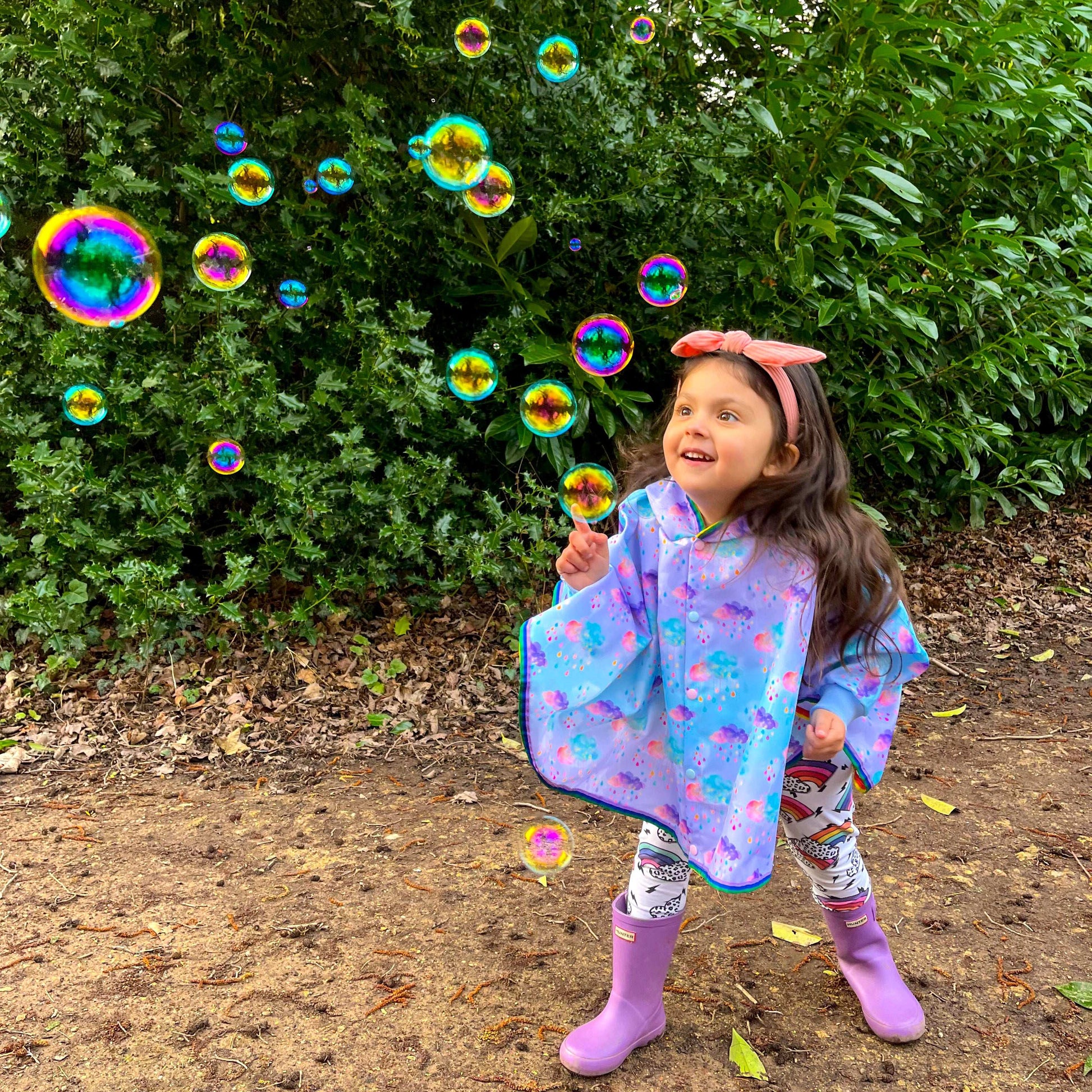 Keep little adventurers dry in style with this handmade waterproof cape, featuring a playful umbrella print, rainbow trim and roomy fit for carefree outdoor fun in any weather.