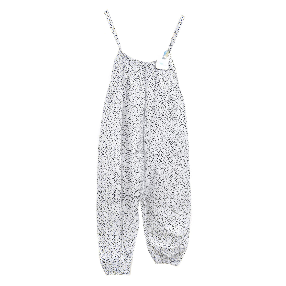A young child wearing a handmade spotty romper. The romper has a monochrome spotty print on soft, lightweight fabric. It has thin, shoulder straps and ruched neckline, relaxed, comfortable fit. 