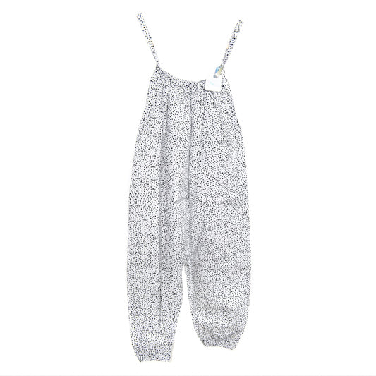 A young child wearing a handmade spotty romper. The romper has a monochrome spotty print on soft, lightweight fabric. It has thin, shoulder straps and ruched neckline, relaxed, comfortable fit. 